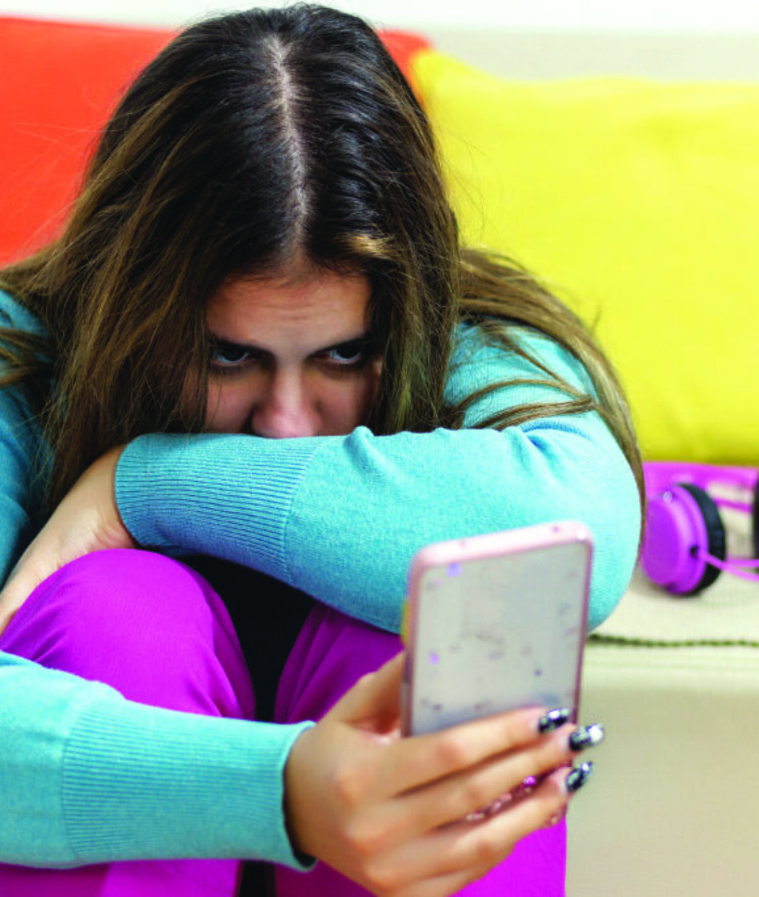 A depressed teenager checking at the mobile phone sitting in her room
