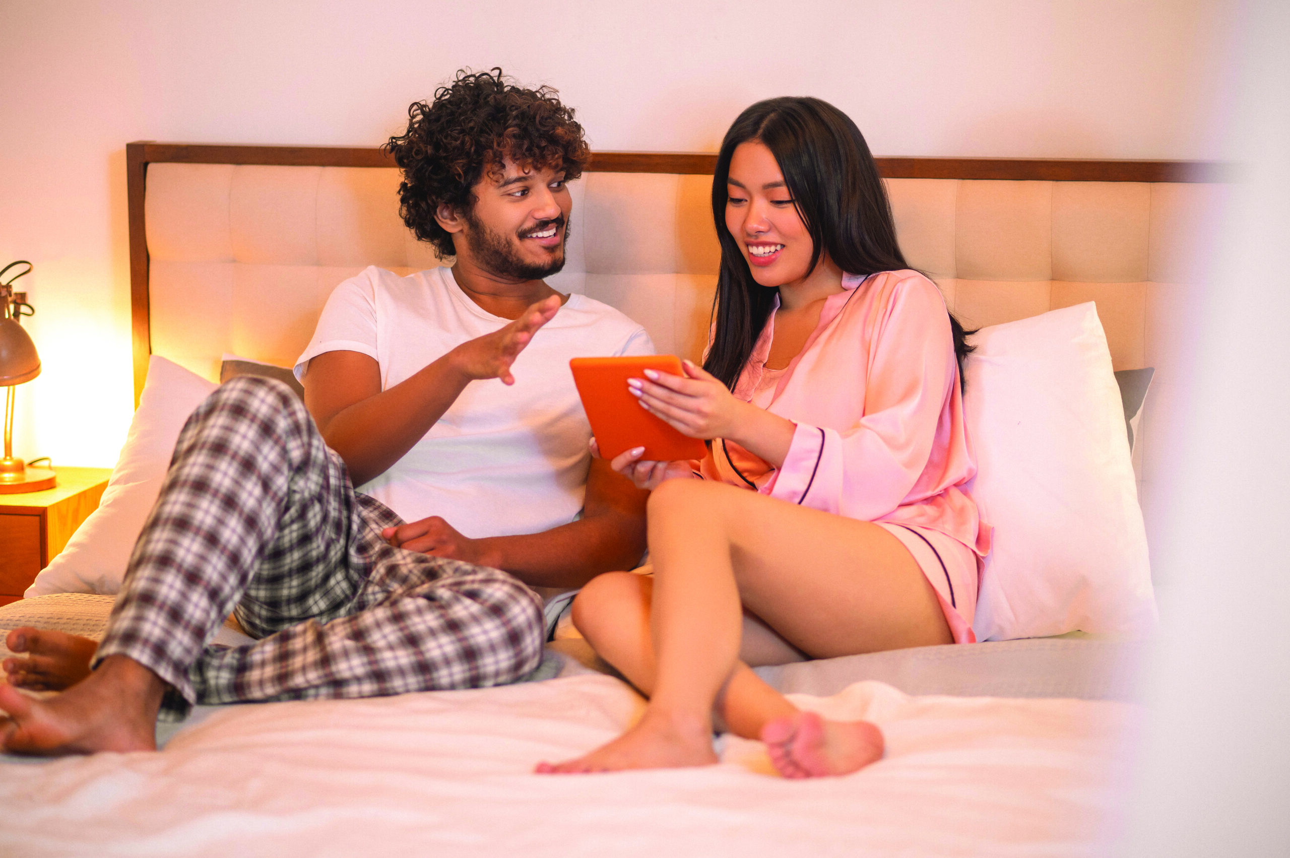 Man looking at woman with tablet lying on bed
